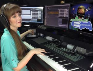 A photo of video game composer Winifred Phillips working in her music production studio on the music of LittleBigPlanet Cross Controller.