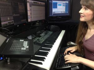 Photo of video game music composer Winifred Phillips working in her music production studio.