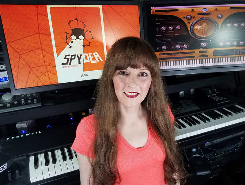 Photograph of video game music composer Winifred Phillips in her music production studio. Phillips is the video game composer for the Spyder game, developed by Sumo Digital for Apple Arcade. Her credits include games in five of the biggest franchises in gaming, and she is considered an authority on video game music who has given lectures at such venues as the Game Developers Conference (GDC), the Society of Composers and Lyricists, and the Library of Congress in Washington DC.